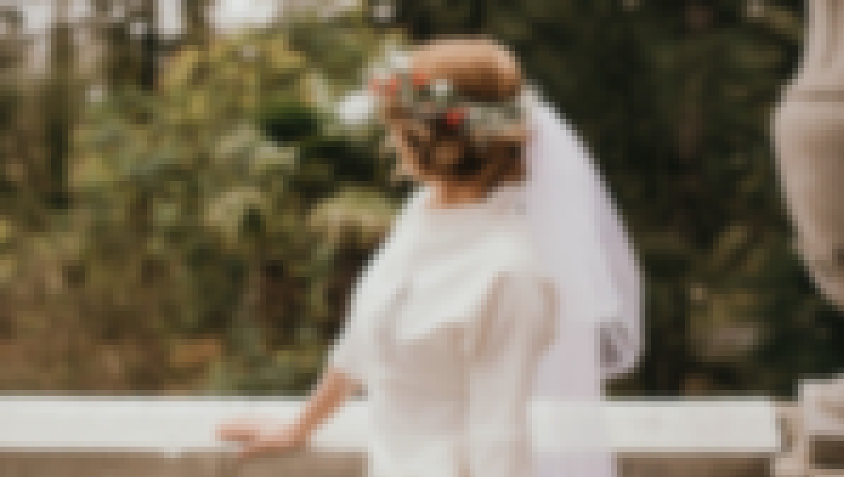 Photo d'une mariée au cocktail de son mariage devant un château