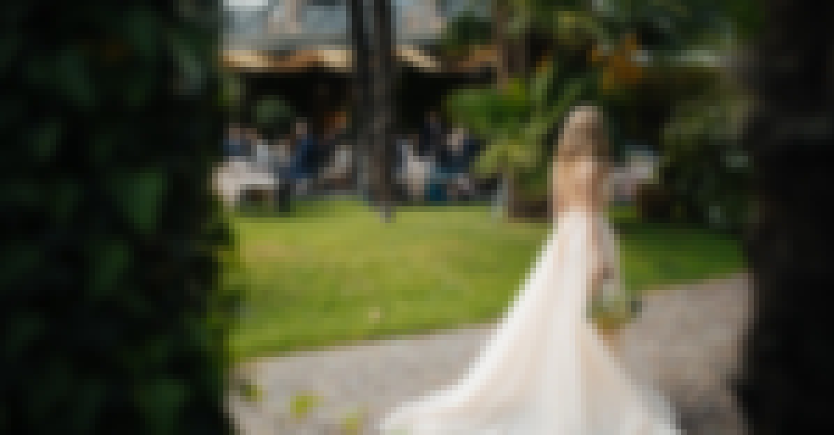 Photo d'une mariée au cocktail de son mariage devant un château