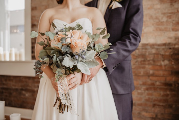 Couple de mariés avec un bouquet de fleurs à l'occasion de leur mariage