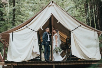 Photo d'un couple photographié le jour de leur mariage devant une cabane en bois écologique.