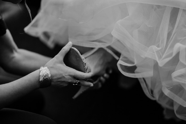 Photo d'une future mariée en train d'enfiler sa robe le jour de son mariage en Auvergne