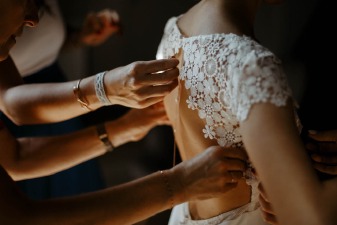 Photo d'une mariée en train d'enfiler sa robe de mariée