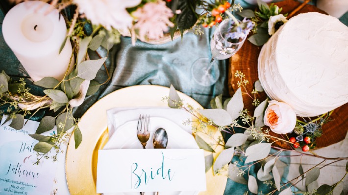 Photo d'une table de mariage décorée avec de jolies bougies, des fleurs et des roses ainsi que des nappes.