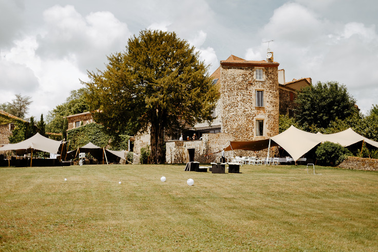 Photos des jardins du Château de Bois Rigaud dans le Puy-de-Dôme en Auvergne, avec une vue sur la façade en pierres du château et sur ses tentes stretch extérieures